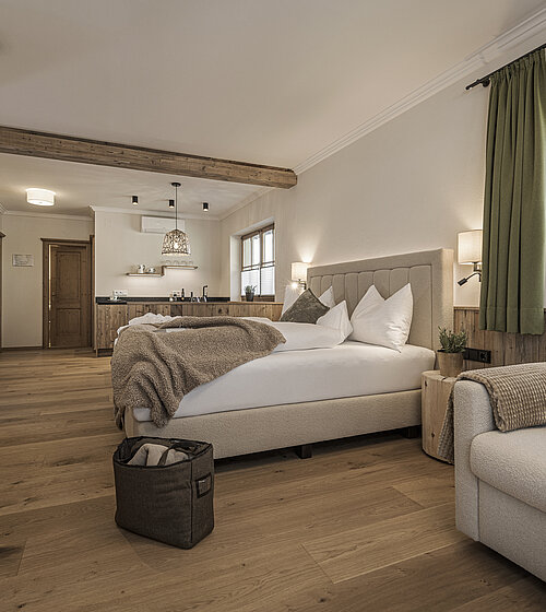Gemütliches Schlafzimmer mit Doppelbett, Sofa und großen Fenstern im Familienappartement Hotel Bachmanngut Wolfgangsee