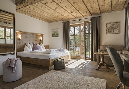 Gemütliches Hotelzimmer eingerichtet mit Holzboden, Holzmöbeln und natürlichen Materialien im Hotel Bachmanngut am Wolfgangsee