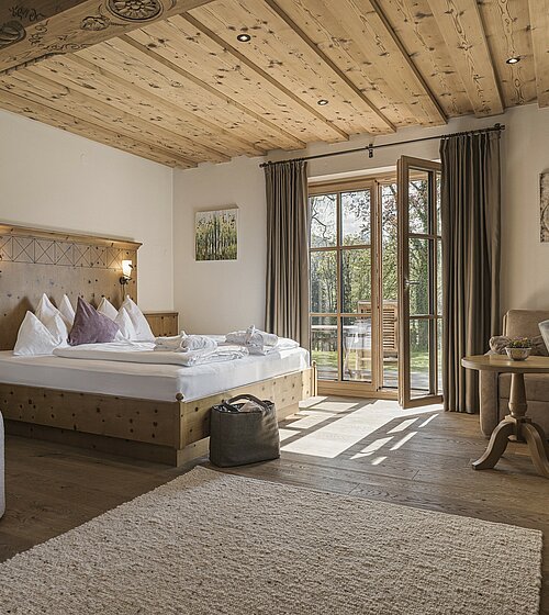 Gemütliches Hotelzimmer eingerichtet mit Holzboden, Holzmöbeln und natürlichen Materialien im Hotel Bachmanngut am Wolfgangsee