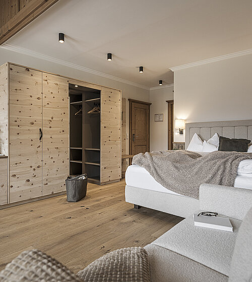 Modernes Hotelzimmer mit Boxspringbett, Naturholzmöbeln und TV im Hotel Bachmanngut am Wolfgangsee