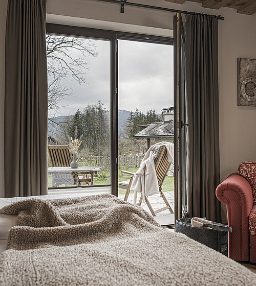 Blick vom Bett auf Gartenmöbel und Terrasse im Komfort Garten Zimmer am Wolfgangsee