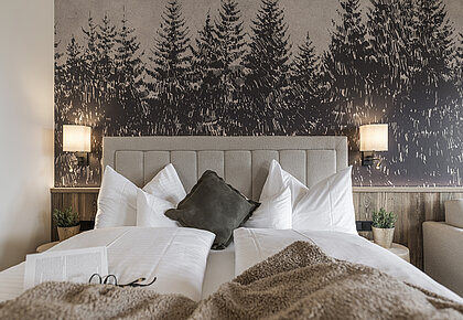 Schlafzimmer mit Zirbenholzbetten, Waldtapete und gemütlicher Alpeneinrichtung im Familienappartement Hotel Bachmanngut Wolfgangsee