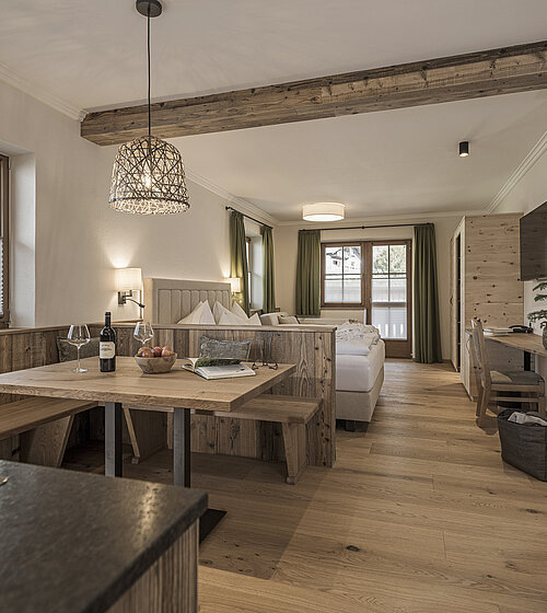 Offener Wohnbereich mit Holzmöbeln, Esstisch und Sitzecke im Alpenstil im Familienappartement Hotel Bachmanngut Wolfgangsee