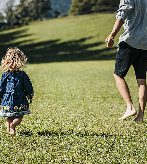 Familie auf der Wiese mit Kleinkind im Urlaub im Hotel Bachmanngut Wolfgangsee