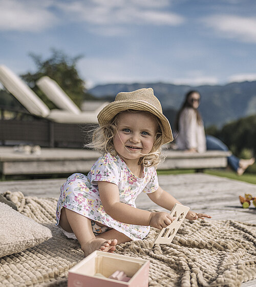 Kleinkind auf Decke im Garten des Hotel Bachmanngut