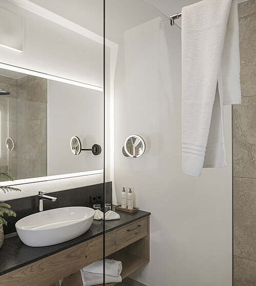 Modernes Badezimmer mit großem Spiegel, Holzwaschtisch und dekorativer Tannenpflanze Hotel Bachmanngut Wolfgangsee