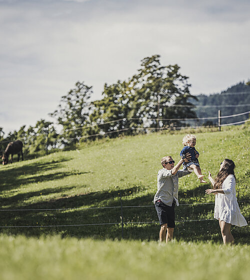 Familie auf der Wiese mit Kleinkind im Urlaub im Hotel Bachmanngut Wolfgangsee