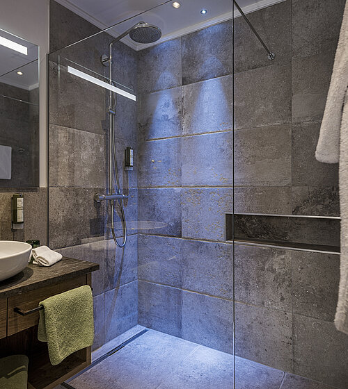 Modernes Bad mit Natursteinfliesen, Walk-in-Dusche und beleuchtetem Spiegel im Komfort Garten Zimmer